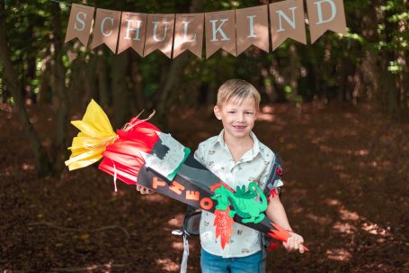 Junge mit Spielzeugrakete steht vor einer festlichen Dekoration im Wald.