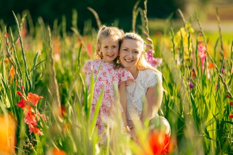 Mutter und Tochter lächeln glücklich zwischen bunten Blumen.