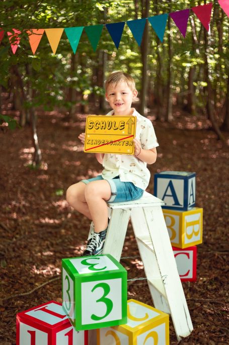 Ein Junge sitzt auf einer Leiter und hält ein gelbes Schild mit der Aufschrift „Double“.