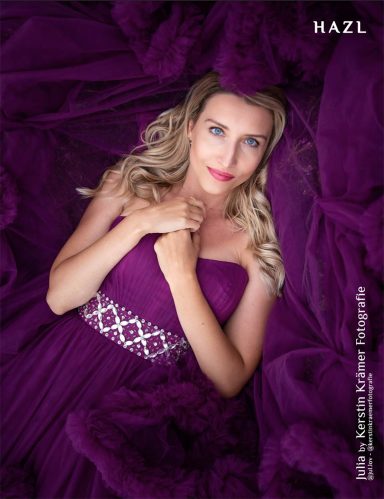 Frau in lila Kleid mit Perlenverzierung, liegend auf einem lila Stoffhintergrund.