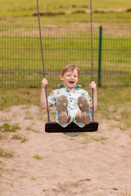 Ein fröhlicher Junge schwingt auf einer Schaukel im Freien.